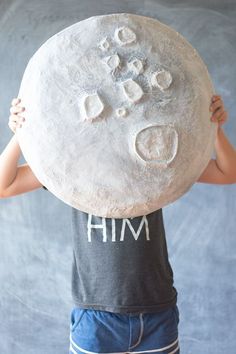 a young child holding up a large round object with writing on it's face