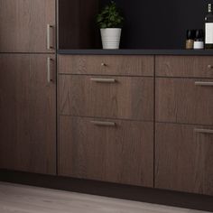 a kitchen with dark wood cabinets and black counter tops, along with a potted plant