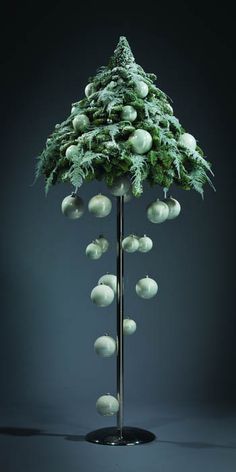 an image of a christmas tree made out of white balls and greenery on a metal stand