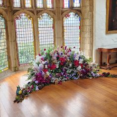 an arrangement of flowers on the floor in front of stained glass windows