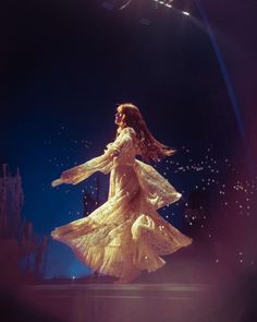 a woman in a white dress is dancing on stage