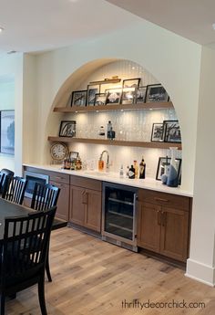 a dining room table and chairs in front of a built - in wine rack with pictures on it