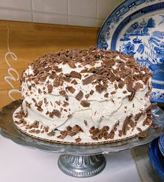 a cake with white frosting and chocolate sprinkles on it sitting on a plate