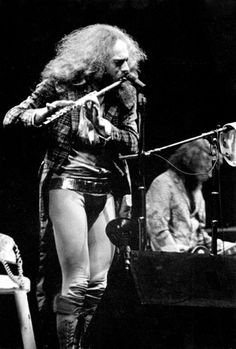 an old photo of a woman with long hair and boots on singing into a microphone