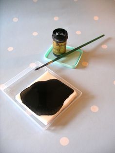 there is a black substance and a paintbrush on the table with polka dotes