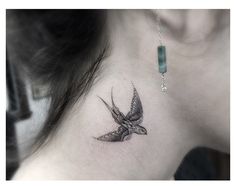 a bird tattoo on the back of a woman's neck