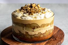 a dessert is sitting on top of a wooden platter with whipped cream and nuts