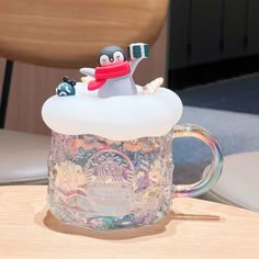 there is a glass mug with a penguin in it sitting on top of a table