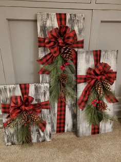 three wooden blocks decorated with pine cones and red bows, sitting on the floor next to each other