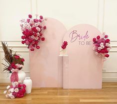 two vases filled with flowers on top of a wooden floor next to a pink sign