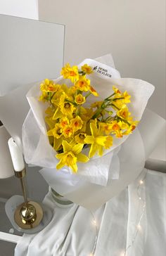 a bouquet of daffodils is sitting on a table next to a candle