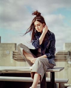 a woman sitting on top of a wooden bench