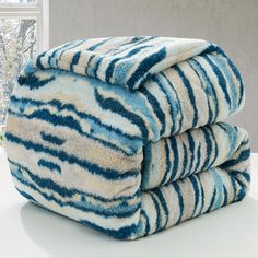 three blue and white towels stacked on top of each other in front of a window