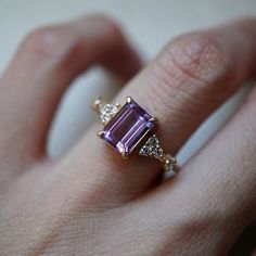 This beautiful Amethyst Versailles Ring features an 8x6mm natural emerald cut amethyst surrounded by sparkly white CZs. Available in your choice of gold vermeil, or 14K solid gold. Create the ultimate stack with our Goddess ring band. Also available in a moissanite version here. Gold vermeil or 14k solid gold Natural 8x6mm emerald cut amethyst Round CZs (what's this?) ** This item is specially made for you. Please allow 1-2 week lead time. ShippingDomestic: Free standard shipping within the U.S. Purple Engagement Rings, Antique Ruby Ring, Purple Stone Ring, Amethyst Wedding Rings, Ruby Ring Vintage, Purple Stone Rings, Purple Amethyst Ring, Present Birthday