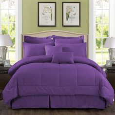 a bed with purple comforter and pillows in a room