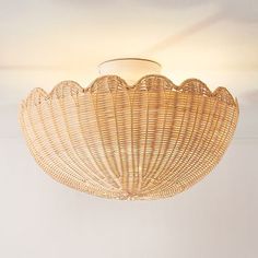 a wicker light fixture hanging from the ceiling in a room with white walls and flooring