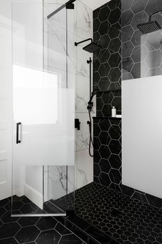 a black and white bathroom with hexagonal tiles on the floor, shower head, and toilet