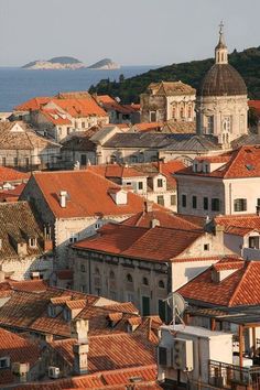 an aerial view of old buildings and the sea in the background, with mountains in the distance