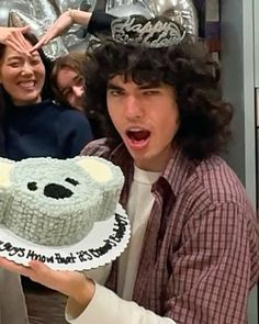 two people are holding a cake in front of them and one is surprised at the camera