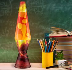 a colorful lamp sitting on top of a wooden table next to books and pencils