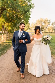 a bride and groom walking down a dirt road