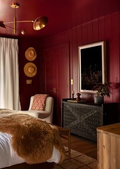 a bedroom with red walls and white bedding has a fur rug on the floor