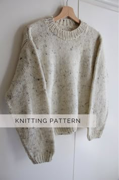 a white sweater hanging on a wall with the words knitting pattern below it that says,