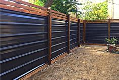 a wooden fence with metal slats in the middle and a potted plant next to it