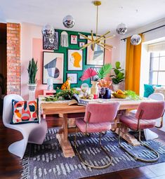 a dining room with pink chairs and pictures on the wall above it, along with an area rug