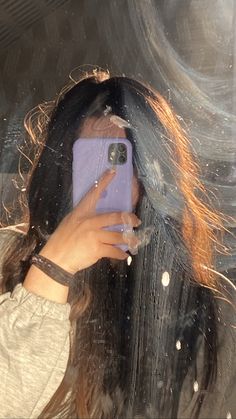 a woman taking a selfie in front of a mirror with her hair blowing in the wind