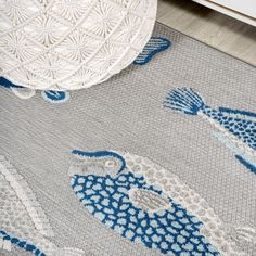 an area rug with blue and white fish on the floor next to a round table