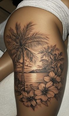 a woman's thigh with flowers and palm trees on it, while the sun is setting