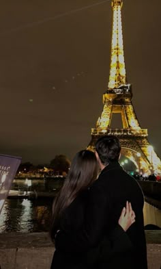 a man and woman standing next to each other in front of the eiffel tower