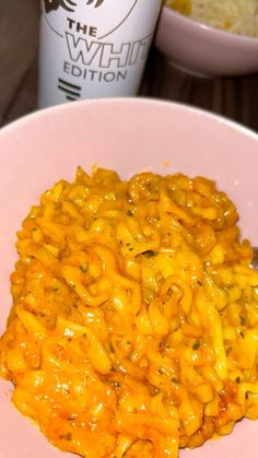 macaroni and cheese on a pink plate with a cup of coffee in the background