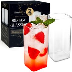 a drink in a glass with strawberries and mint on the rim next to a box