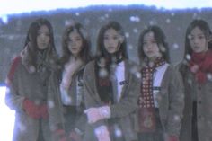 four girls standing in the snow wearing winter clothes