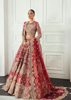 a woman in a red and gold bridal gown standing next to a white wall