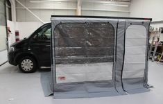 a black van parked in a garage next to a gray tarp covering the door