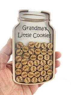 a person holding up a cookie jar that says grandma's little cookie with lots of cookies in it