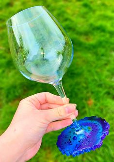 a hand holding a wine glass in the grass