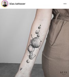 a woman's arm with an image of the planets and stars tattooed on it