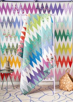 a colorful quilt hanging on a wall next to a basket