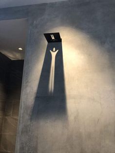 the shadow of a person standing in front of a wall with a laptop on it