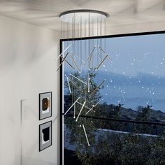 a modern chandelier hanging from the ceiling in front of a window with mountains outside