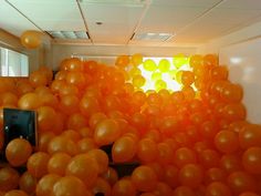 there are many orange balloons floating in the air and on the wall, all over the room