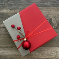 a red christmas ornament sitting on top of a present box with ribbon around it