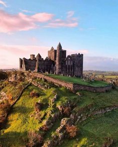 an old castle sitting on top of a lush green hillside