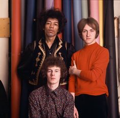 three men standing next to each other in front of colorful wall