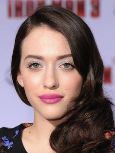 a woman with long dark hair and pink lipstick