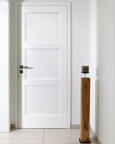 an empty room with a white door and wooden post in the floor next to it